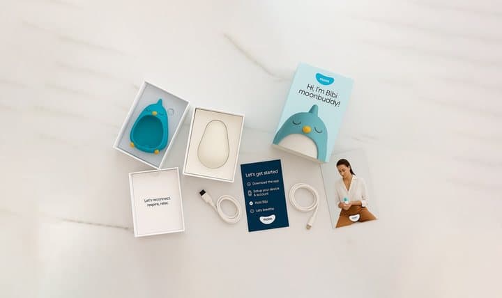 Moonbuddy box opened to show the blue bird device, charging cable, instructions and leaflets