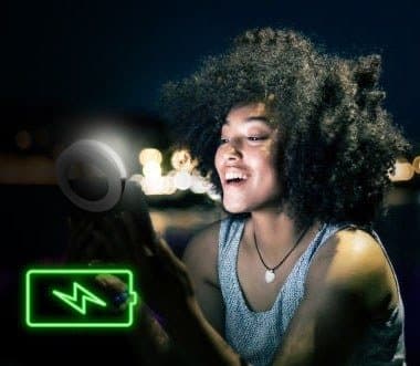 Woman taking a selfie at night with an OlumiRing next to a charging battery icon