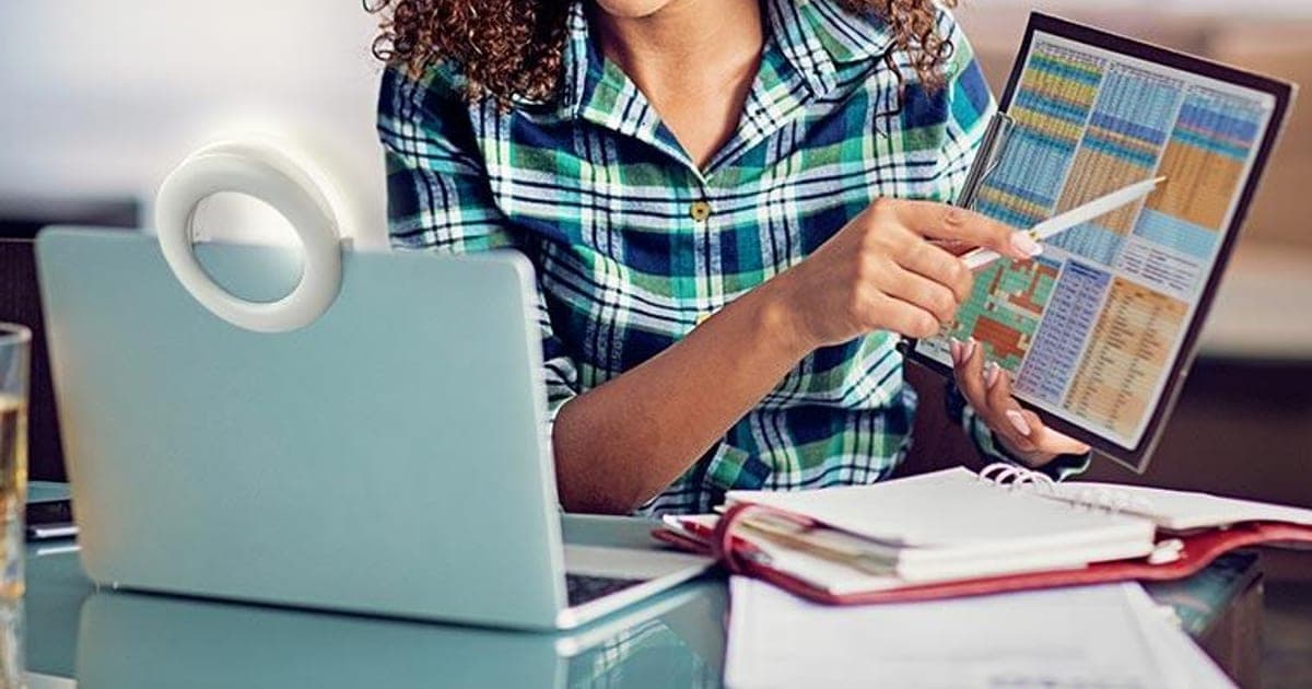 OlumiRing clip-on ring light attached to a laptop screen while a woman works at a desk
