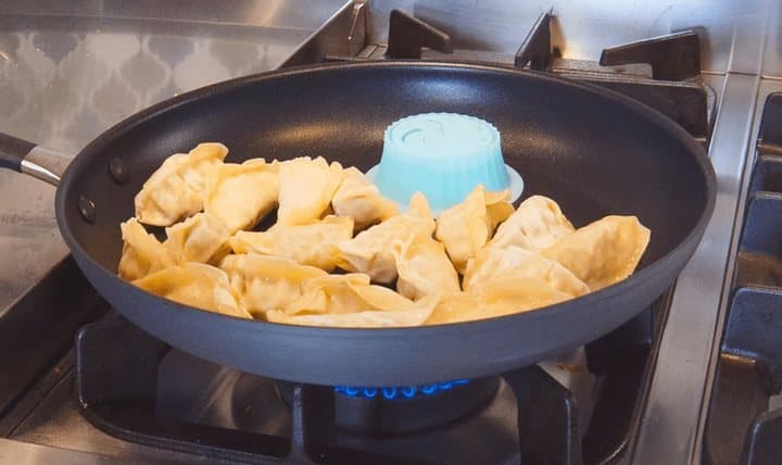 Pacuzzi in a large frying pan surrounded by dumplings on a gas hob