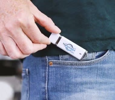 Hand putting a small white ThePhotoStick into a jeans pocket