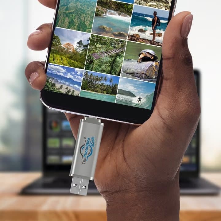 ThePhotoStick Mobile plugged into the bottom of an Android phone showing a grid of photos