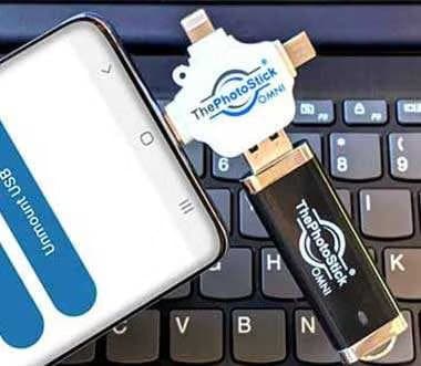 ThePhotoStick Omni plugged into an Android phone lying on a laptop keyboard