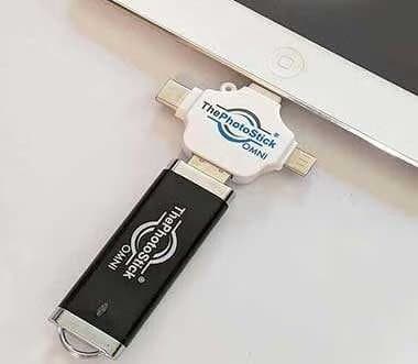ThePhotoStick Omni plugged into the port of a white tablet