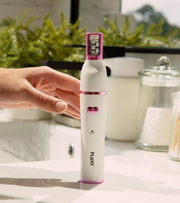 Pluxy Epil Pro epilator standing upright on a counter beside plants and jars