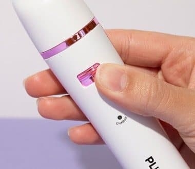 Hand holding the Pluxy epilator showing its power switch and charging indicator
