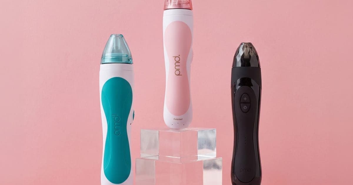 PMD Personal Microderm Classic, Pro and Elite Pro devices displayed on clear stands against a pink background