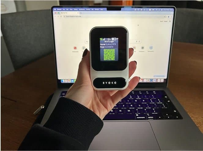 Ryoko PRO held in front of a laptop showing a web browser