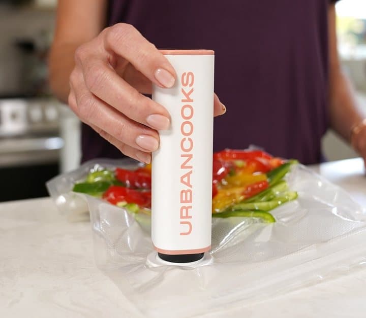 Hand pressing the SealPro handheld pump onto the valve of a bag of vegetables