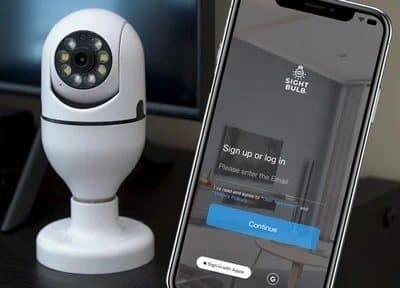 Sight Bulb camera on a table beside a phone showing the Sight Bulb app sign-in screen