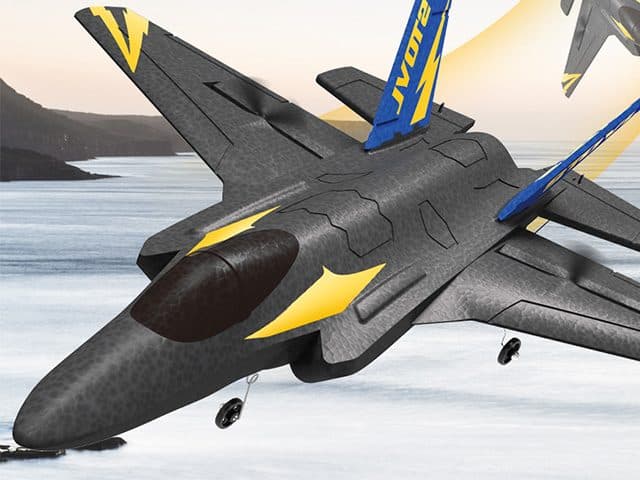 SkyHunterX foam jet flying low over water with mountains behind, landing gear down