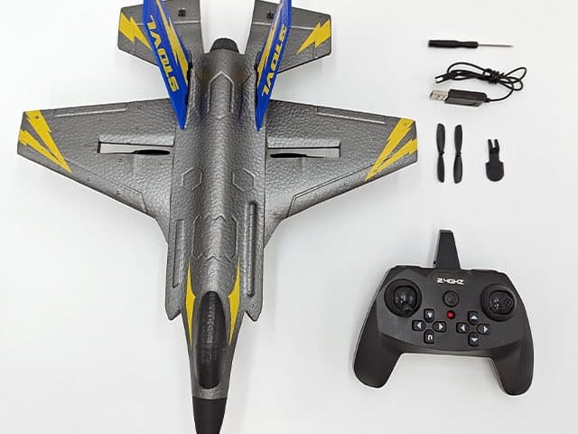 SkyHunterX kit laid out: the grey foam jet, a black 2.4GHz controller, a small screwdriver, a USB charging cable, two spare propellers and a small part