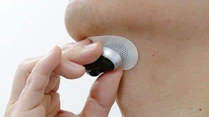 A hand pressing the SleepLab unit on a white conductive patch to the skin under a man's chin