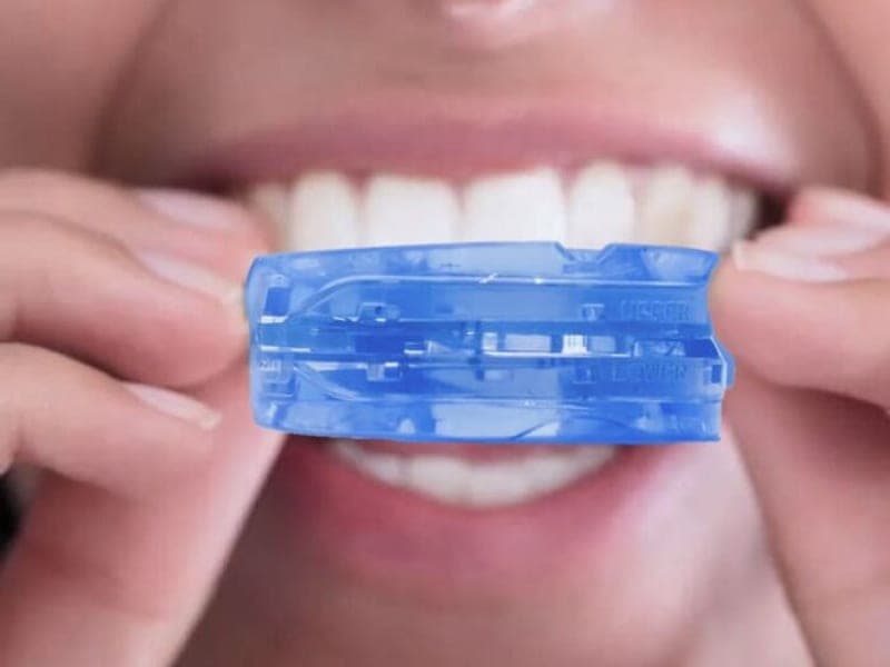 Close-up of the SleepZee mouthpiece being inserted over the upper and lower front teeth