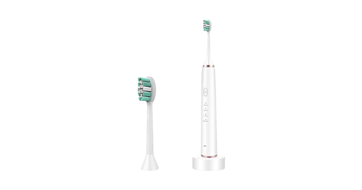 White SonicX PRO electric toothbrush standing upright on a small base, beside a spare green and white brush head