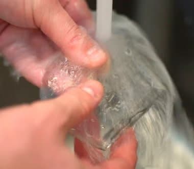 Hands rinsing a clear Soul Insole gel insert under running water