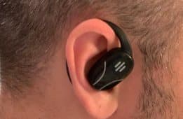Close-up of a black Talky AI Bud with its hook around a person's ear