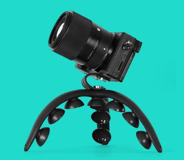 Small mirrorless camera mounted on a black Tenikle on a teal background