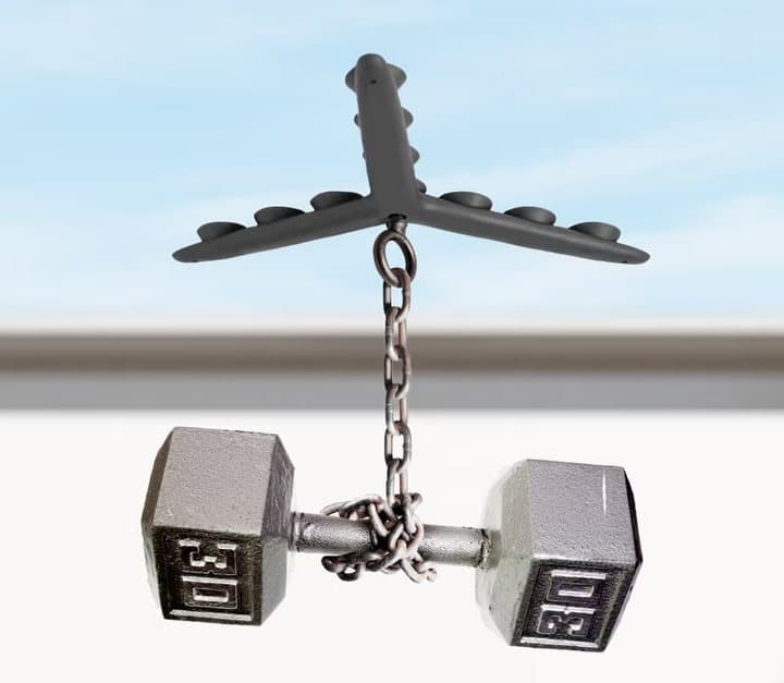 Tenikle stuck to a surface holding a hanging dumbbell on a chain