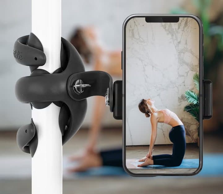 Black Tenikle wrapped around a pole holding a phone filming a yoga session