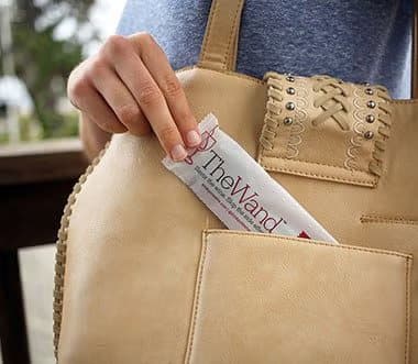 Hand putting a wrapped PureWine wand into a handbag pocket