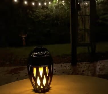 TikiTunes glowing on a patio table at night under string lights