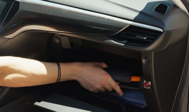 Hand placing a TireHero inflator into a car glovebox