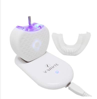 U-shaped toothbrush handle glowing purple on a white charging base printed V-White, with a separate white silicone mouthpiece beside it