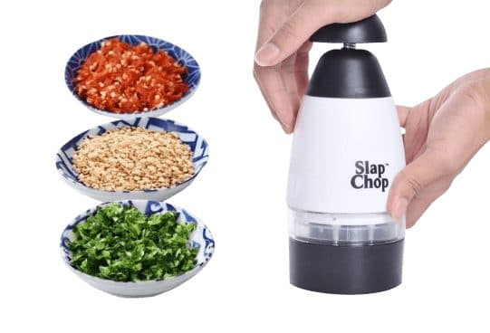 Hands pressing a white plunge chopper printed Slap Chop, next to three blue and white bowls of chopped red chilli, nuts and green herbs