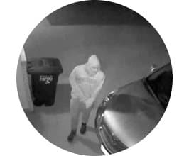 Black and white night vision image of a hooded person by a bin and car, illustrating the Video DoorBell Night Vision Camera Option add-on