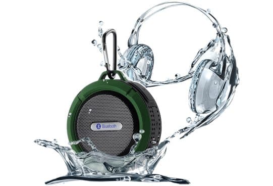 WaterBOOM 360 round speaker with a green rubber rim, grey grille, Bluetooth badge and carabiner, splashed with water beside a water-sculpture headphone graphic