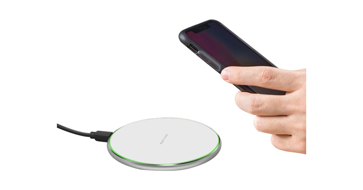 Winergy round white wireless charging pad with a silver rim and green light ring, beside a hand lowering a smartphone onto it