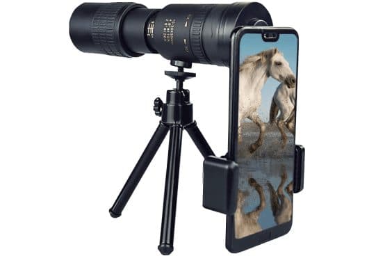 ZoomShot Pro black zoom monocular mounted on a small tripod with a phone clamp holding a phone that shows two white horses